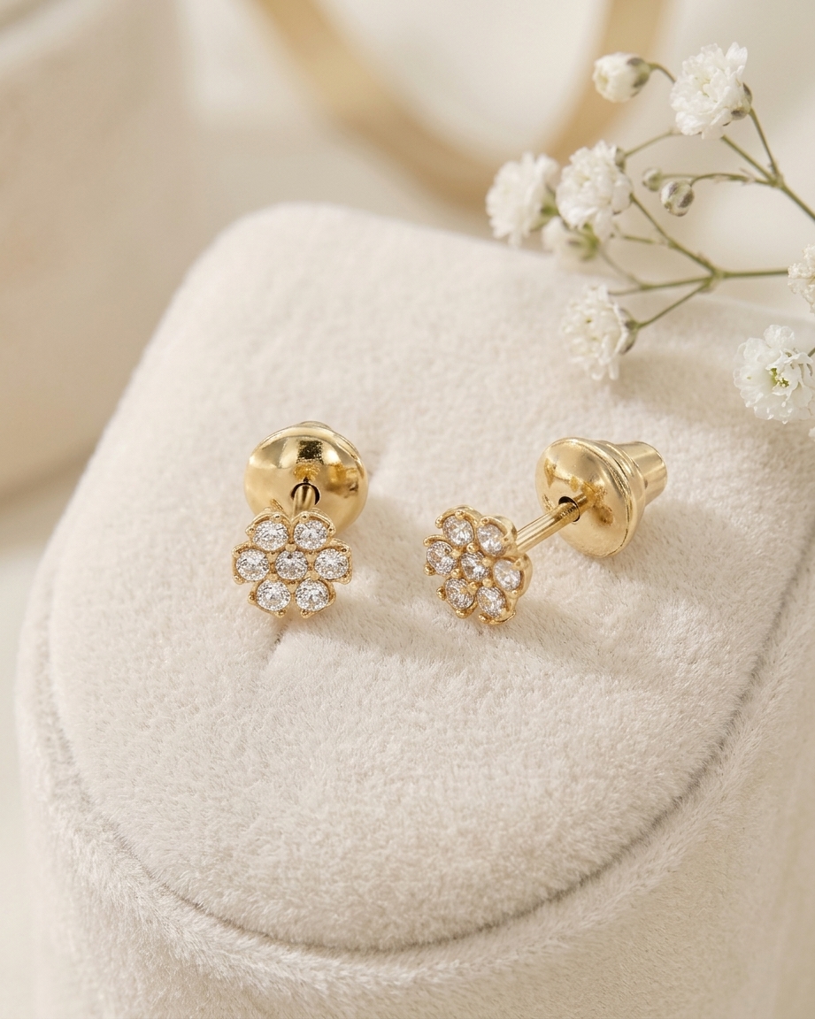 Safe 14K gold screw-back earrings for children in the shape of a flower, featuring sparkling cubic zirconia stones, presented on a soft velvet cushion.